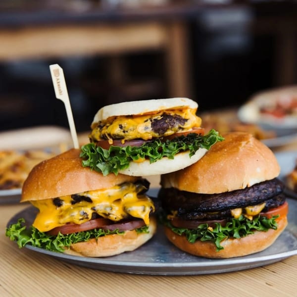 Three Unforked burgers, two with melted cheese and one with a dark patty, on a metal tray.