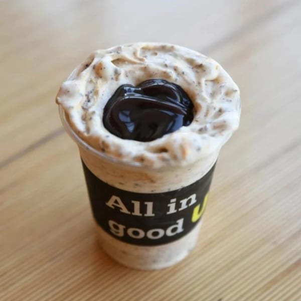Unforked's milkshake with whipped cream and chocolate syrup on a wooden table.