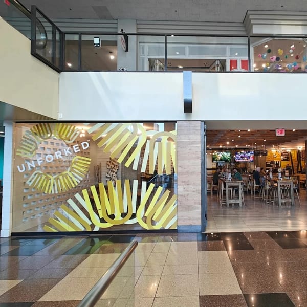 Unforked restaurant entrance with yellow fry-shaped window decals and a view of the dining area.